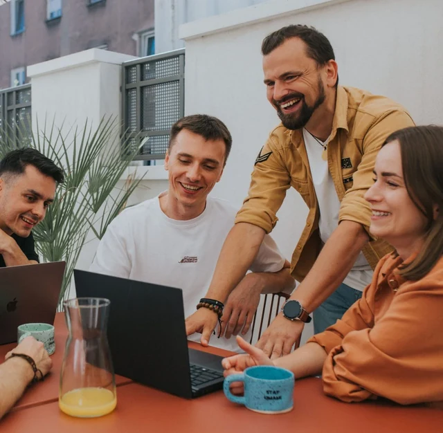 Zespół umami digital przy laptopach na tarasie, wspólnie omawia projekt